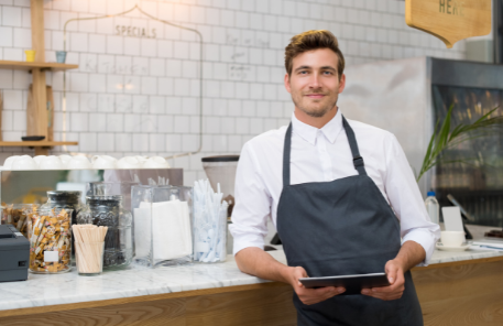 Barista leaning against a counter holding a tablet