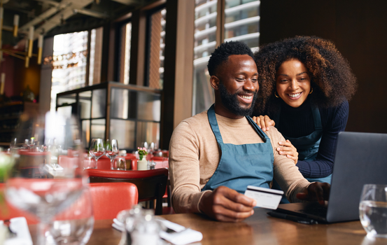 Man holding a credit card while sitting at a laptop