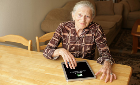 Elderly woman sitting at a table with a tablet