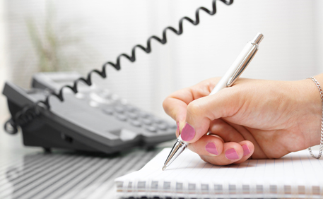 Hand holding a pen while writing on a notebook