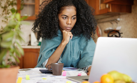 Woman sitting at her kitchen table looking at a laptop