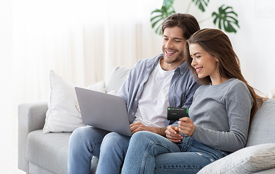 Man and woman sitting on the couch, looking at a laptop
