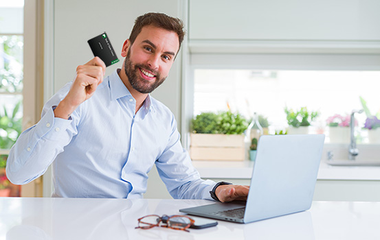 Man holding a credit card while sitting at a laptop