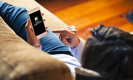 Person sitting on couch, looking at Bank of Clarke County on smartphone
